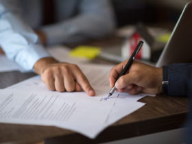 Dwóch przedsiębiorców ściskających dłonie przy stole z umową partnerską w biurze startupu