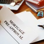 Młoda para przegląda dokument bankowy przy stole z kawą i laptopem w kuchni