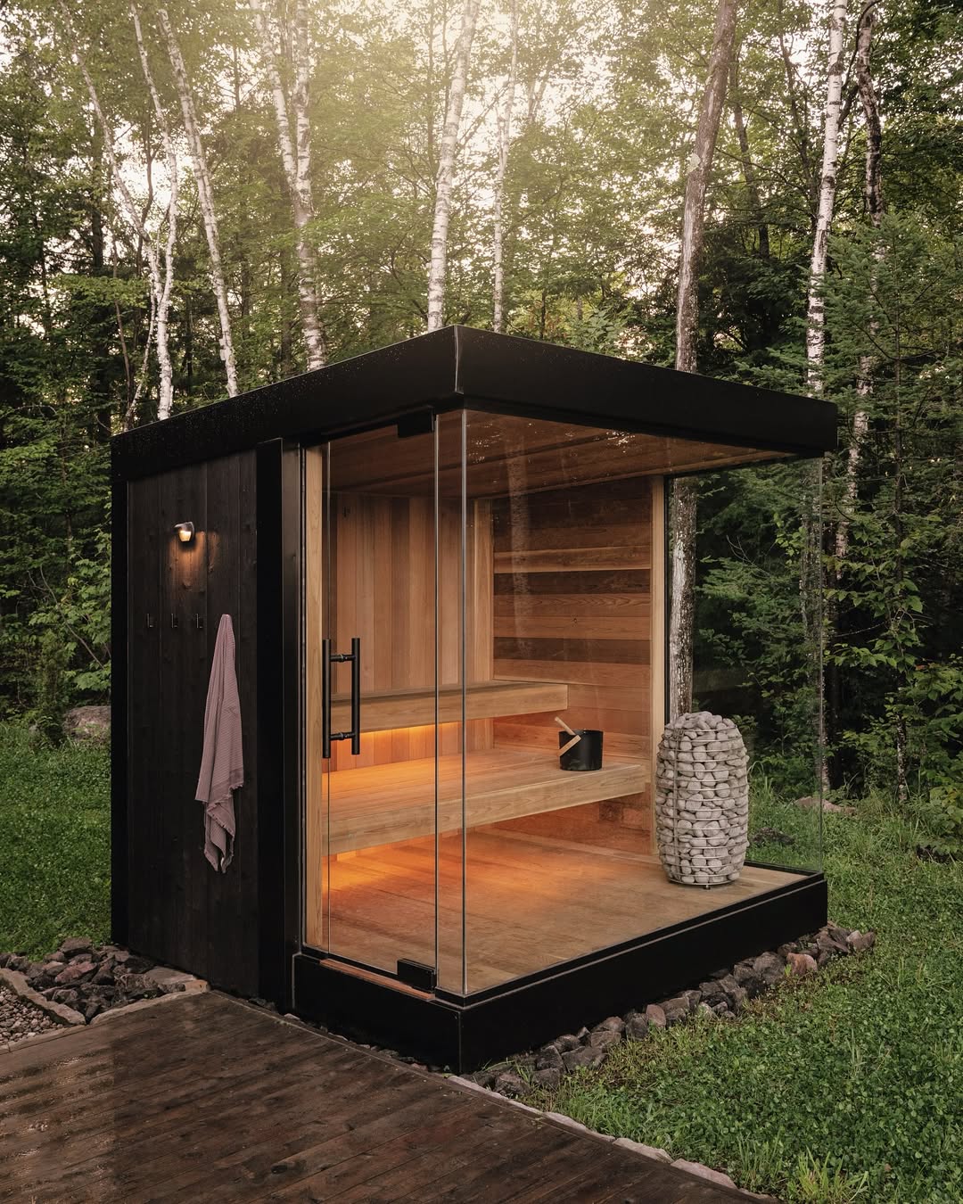 Zimowa sauna ogrodowa z oświetleniem Sauna w ogrodzie zimą pokryta śniegiem i oświetlona lampami