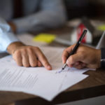 Dwóch przedsiębiorców ściskających dłonie przy stole z umową partnerską w biurze startupu