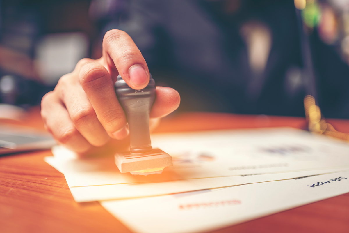 Urzędnik przyklejający apostille do dokumentu pełnomocnictwa przy ladze